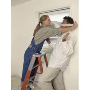  Young Woman Putting Tape Around the Mouth of a Young Man 