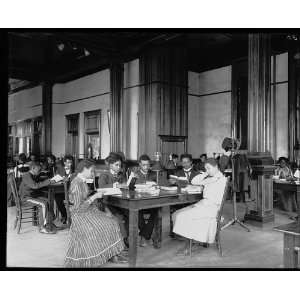   and female students sitting at tables, reading, at the